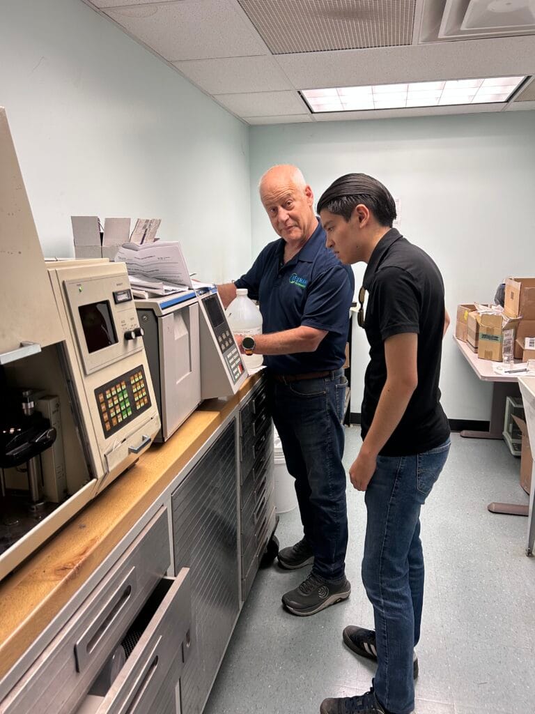 Bill Heumann training newest Heumann Environmental employee to run tests for clients on the aerodynamic particle size machines.